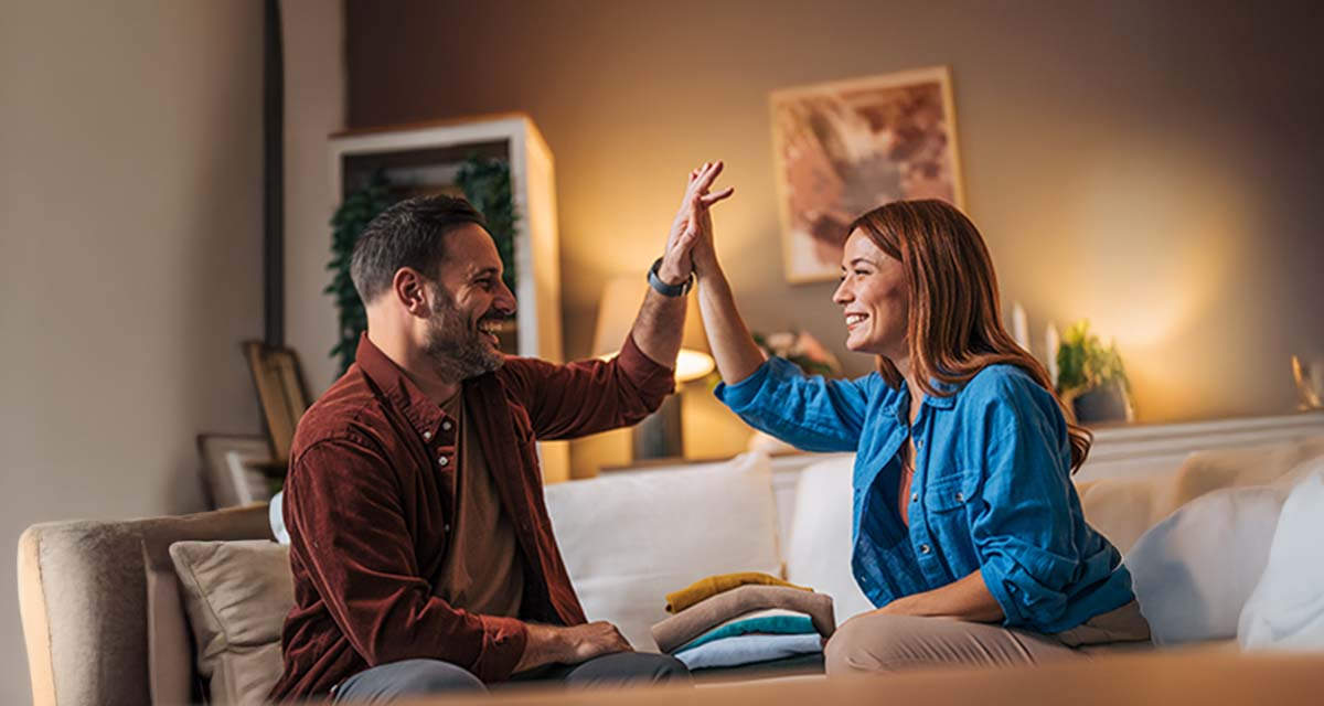 Una coppia sorride soddisfatta in un soggiorno: le offerte luce con bonus rendono più leggere le bollette
